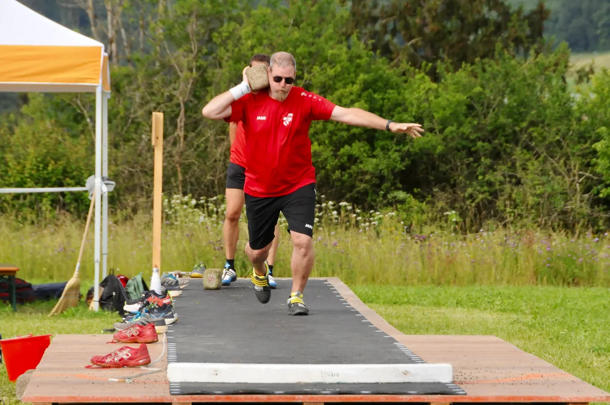 Anlauf nehmen und ... Man sieht einen Steinstösser, der Anlauf holt.